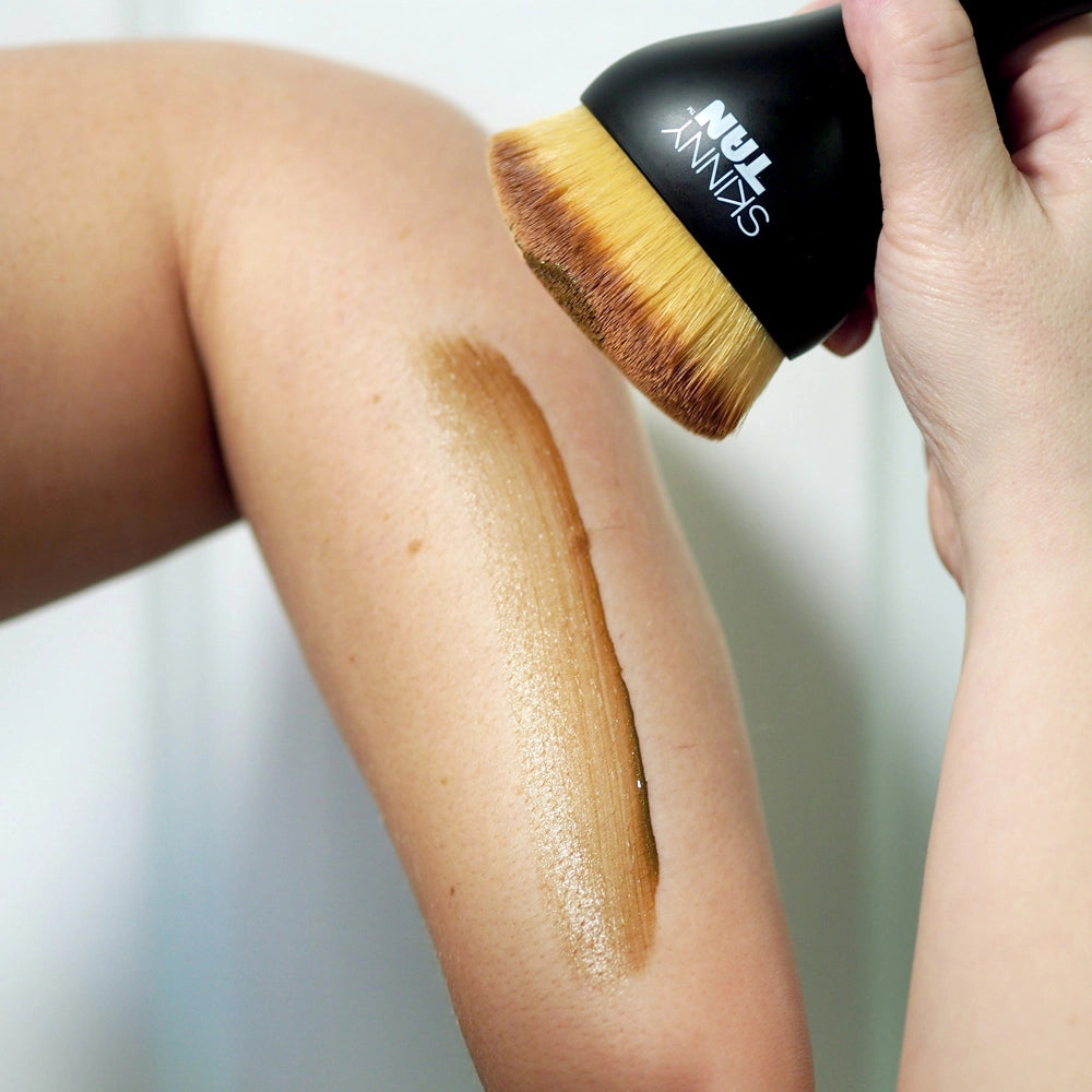 Skinny Tan Body Buffing Brush image of someone using the brush and applying tan onto arm